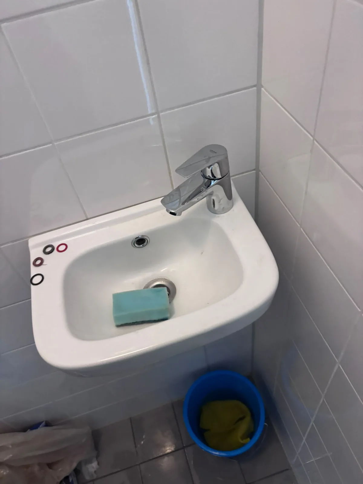 Wandgemonteerde wastafel met Grohe-kraan, rubberen afdichtingsringen op de rand.