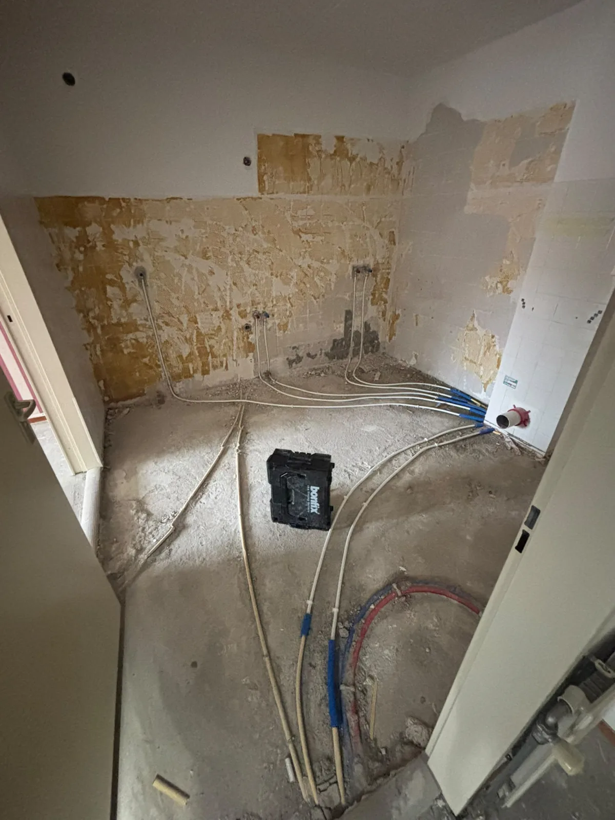 Ruimte in renovatie met uitgebreide nieuwe leidingen voor water aanvoer en afvoer.